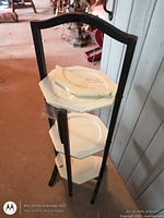 Full view of three-tier wooden rack with white plates