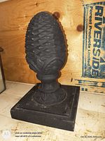 Front view of cast iron pine cone finial on square base