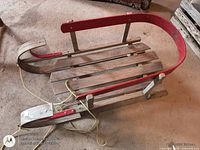 Top view of wooden sled showing slatted deck, red side rails, rope