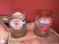 Both mugs front view showing logos and dates