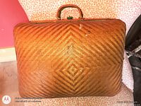 Front view of rectangular wicker suitcase showing diamond weave pattern and handle