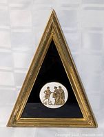 Front view of triangular gilt frame with ceramic plaque