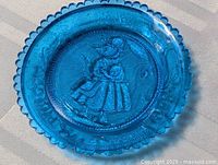 full view of blue glass plate showing scalloped rim and central mouse design