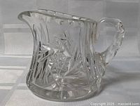 Front view of clear glass creamer showing starburst pattern