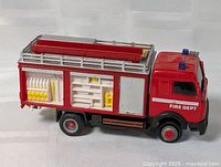 Left side view of red die-cast fire truck toy showing compartments and ladder
