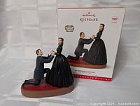 Ornament displayed with box, showing figures and base