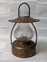 Full view of lantern showing metal base, hobnail glass globe, shade, handle