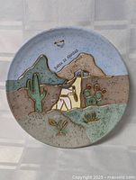 Front view of pottery plate showing full desert scene and inscription