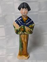 Front view of glazed ceramic Japanese female figurine wearing multicolour kimono