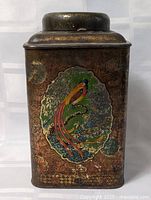 Front view of vintage metal tin showing bird and floral design