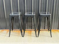 Front view of three identical black iron bar stools