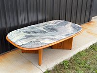 Full view of table angled against wall showing marble top and base