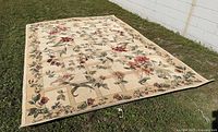 Full view of the large rectangular floral area rug laid out on grass