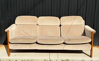 Front view of sofa showing three seat cushions, back cushions, teak frame and flared arms