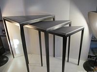 Three triangular metal stacking tables nested together