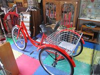 Full view of red adult tricycle showing frame, wheels, basket