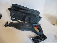 Bosch RS7 reciprocating saw with attached power cord beside Bosch fabric bag