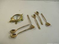 Brass turtle magnifier and six nickel bronze teaspoons laid out