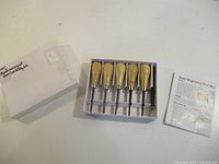 box opened showing five chisels, instructions and lid