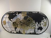 Front view of metal world map gear wall clock
