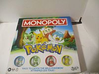 Front of Pokémon Monopoly board game box showing characters and window with four tokens
