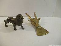lion figurine and brass boot jack side by side