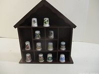 Full view of wooden display case with twelve porcelain thimbles