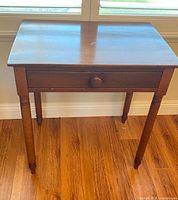 Full view of wooden side table, front, showing drawer and legs