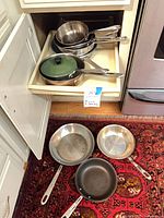Drawer and floor showing multiple stainless and nonstick pans
