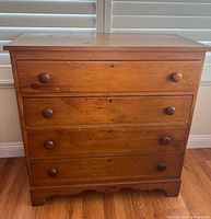 Front view of four-drawer wood dresser showing knobs, keyholes and finish