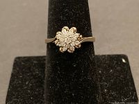 Front view of yellow gold ring with diamond cluster on stand