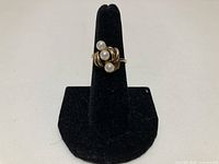 Ring front view on stand showing three pearl cluster and gold setting