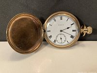 Open view showing white dial with Roman numerals and sub-seconds