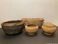 Four baskets displayed, including the two Northwest Coast woven baskets (one with lid, one open)