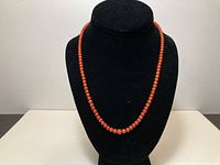 Full view of coral bead necklace displayed on bust form