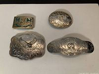 All four silver-plated belt buckles arranged for size comparison