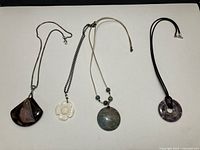 Four necklaces laid out showing pendants and chains