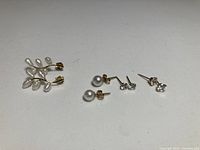 All four earring pairs displayed: branch pearl climbers, pearl studs, two pairs stone studs