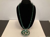 Necklace on bust with earrings displayed below