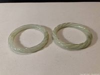 Both light green carved stone bangles side by side