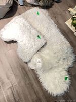 Two white faux fur rugs, pelt shape and rectangular/contoured