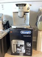 Front view of DeLonghi Magnifica machine sitting on its branded box