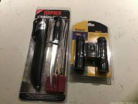Both sealed packages: Rapala fillet knife kit left, Bushmaster binoculars right