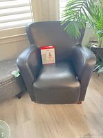 Front view of bonded leather armchair with care kit on seat