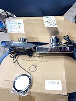 Two Moen shower heads resting on Vynyin lighting kit boxes with one puck light visible