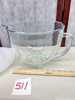 Side view of glass bowl showing handle, spout, embossed KitchenAid logo, and ruler for scale