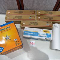 Group shot of toner cartridges, paper reams, labels box, paper roll