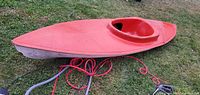 Side view of full red fiberglass kayak on grass