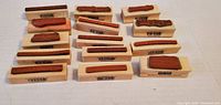 Group of 14 slim wooden blocks with red rubber stamp surfaces visible