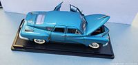 Left front view showing blue 1948 Tucker model on base with hood and doors open